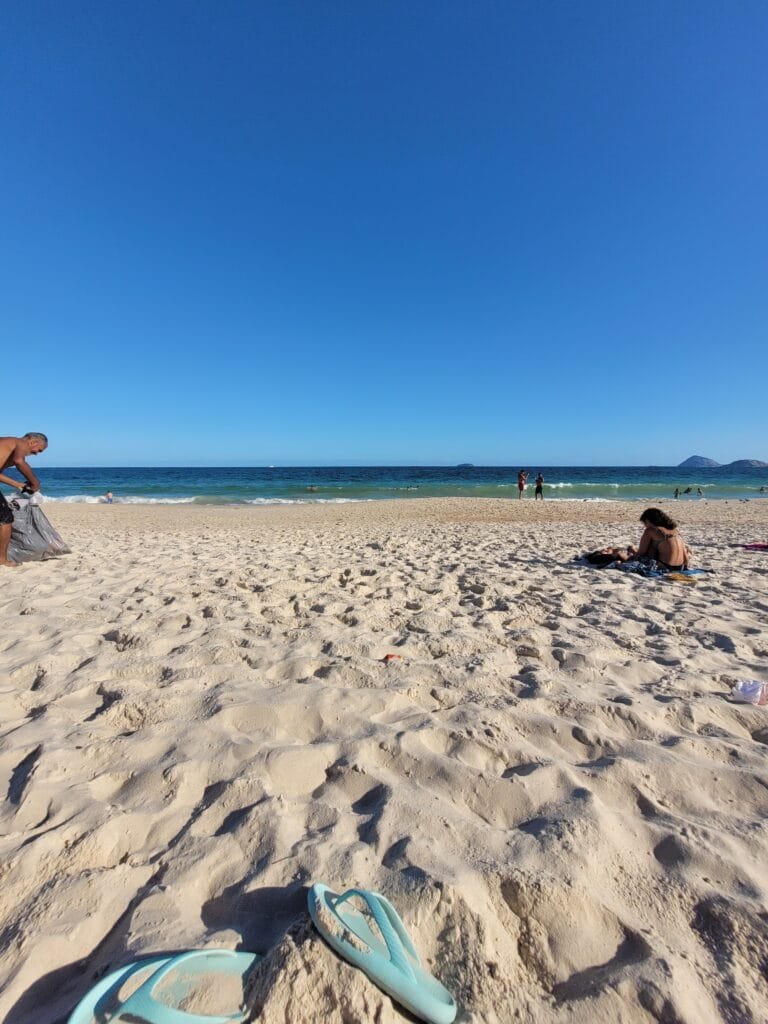 Faixa de areia da Praia de Copacabana com mar azul ao fundo