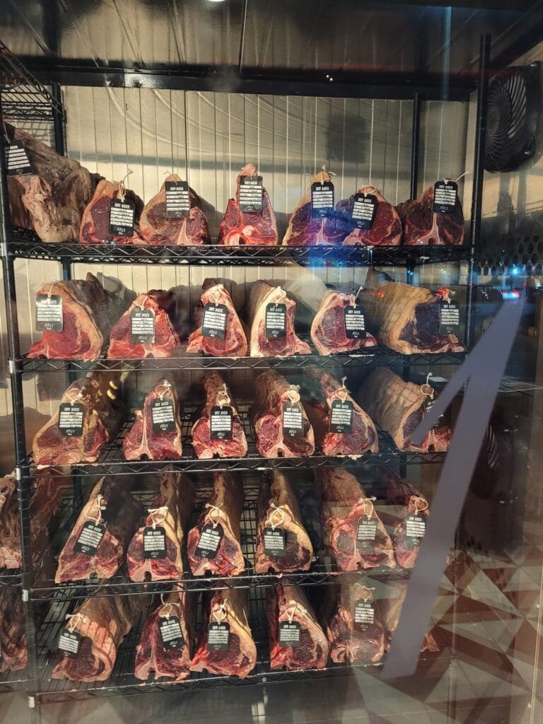 Carnes dry aged expostas na câmara de maturação do Vamo Steak Bar