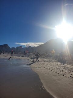 Praia de Copacabana no Rio de Janeiro em um dia ensolarado com pessoas caminhando na areia