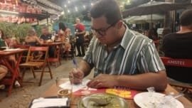 Casal carioca avaliando bares do Comida di Buteco RJ 2024 durante o concurso