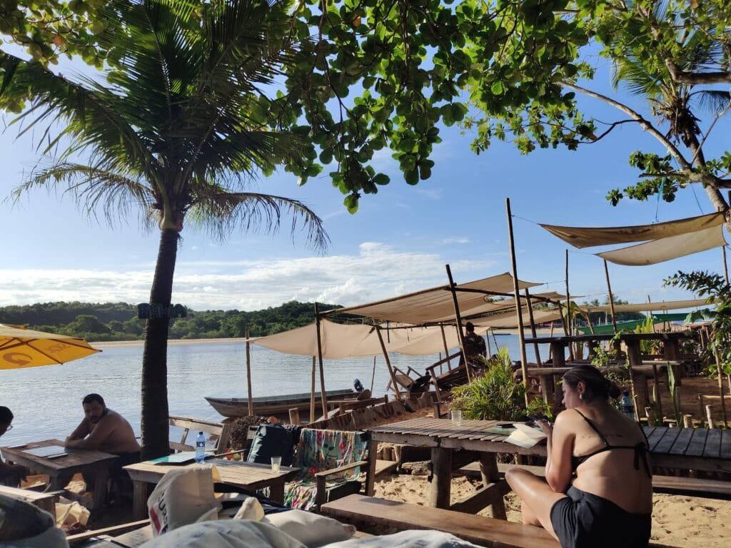 Restaurante à beira do Rio Caraíva com mesas na areia e vista para o rio