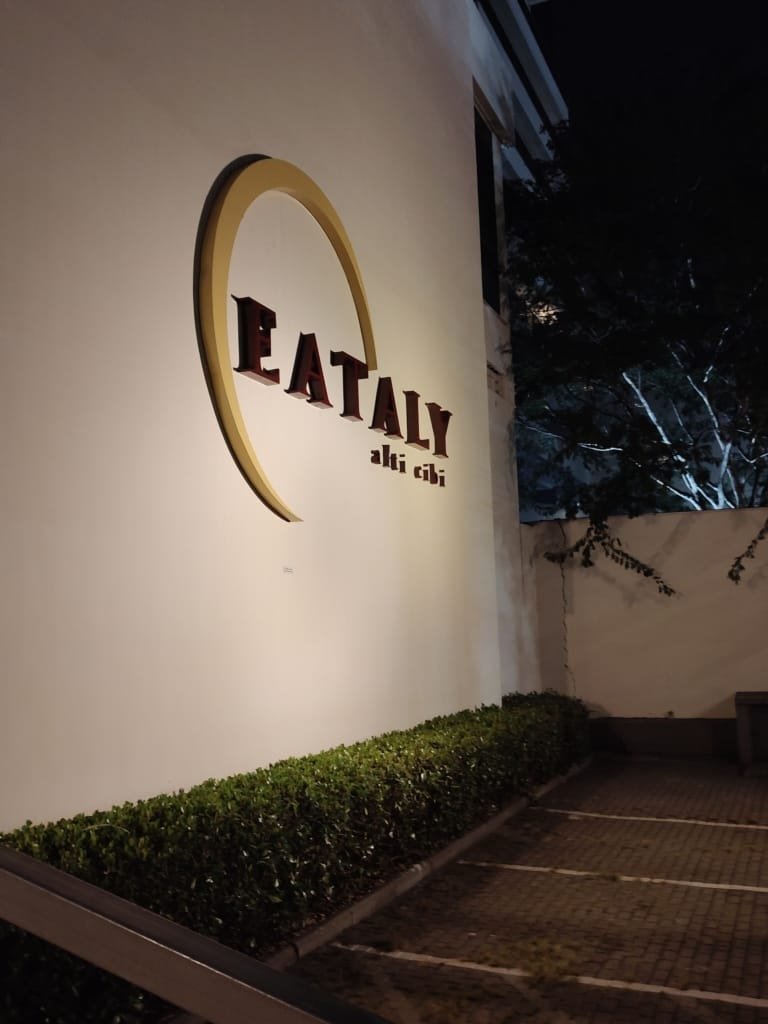 Fachada lateral do Eataly São Paulo iluminada à noite com logotipo clássico em destaque