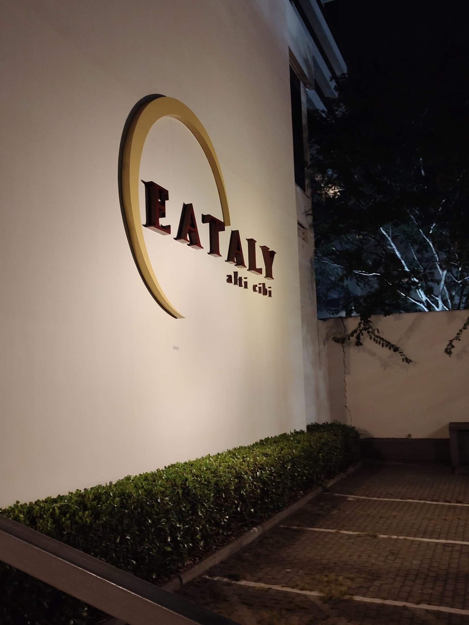 Fachada lateral do Eataly São Paulo iluminada à noite com logotipo clássico em destaque