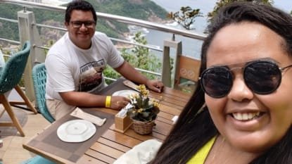 Casal tirando selfie do café da manhã no Morro da Urca na varanda do Clássico Beach Club com vista deslumbrante para o mar e ilhas do Rio de Janeiro