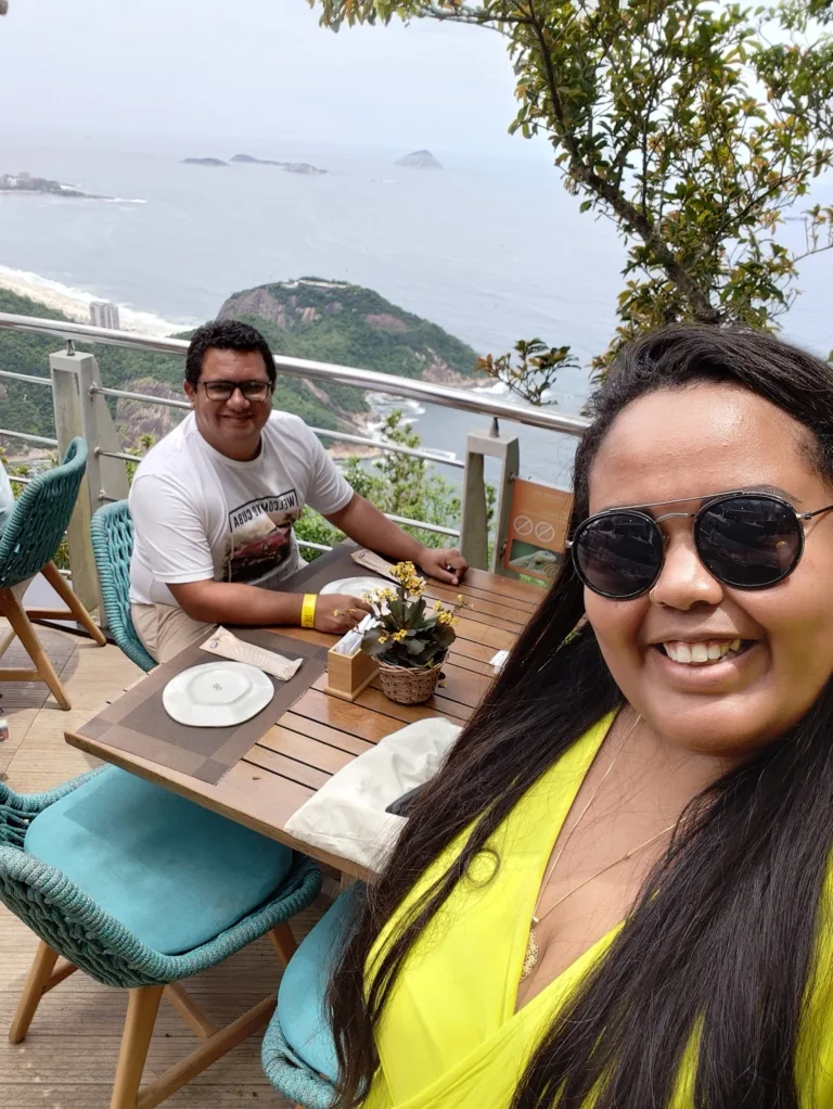 Tomar Café da Manhã no Clássico Beach Club no Morro da Urca: Um Despertar com Vista para o Paraíso 12 Casal tirando selfie do café da manhã no Morro da Urca na varanda do Clássico Beach Club com vista deslumbrante para o mar e ilhas do Rio de Janeiro