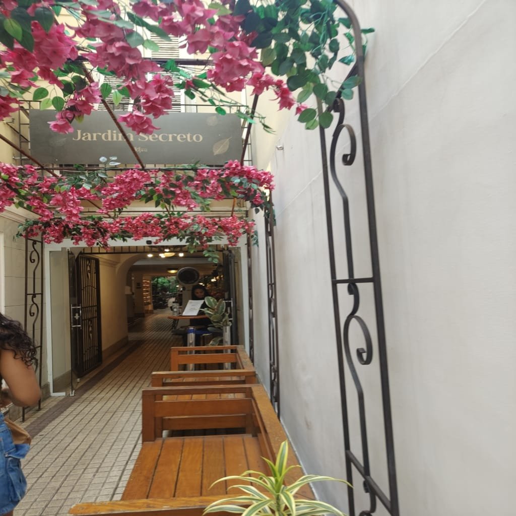 Entrada charmosa do restaurante Jardim Secreto com flores decorativas no teto