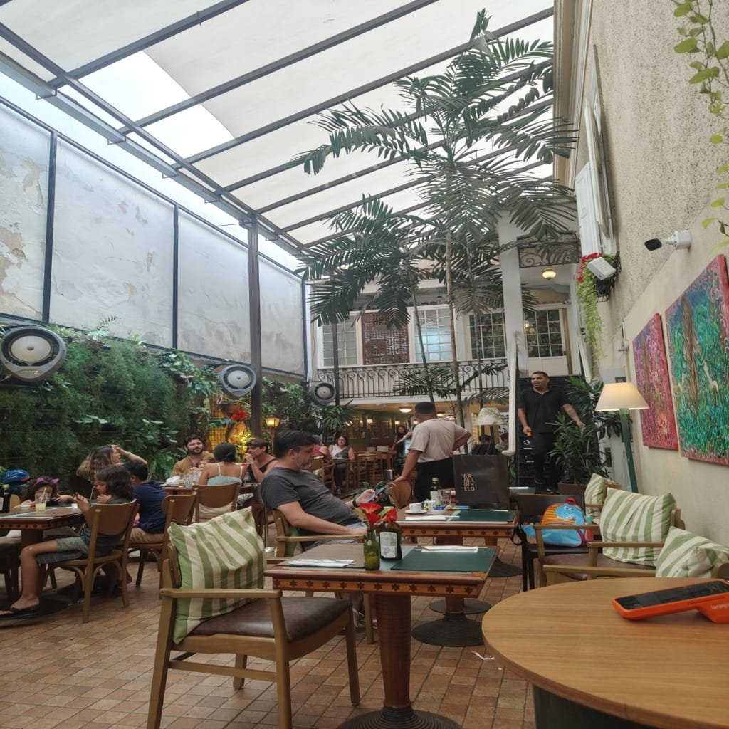 Área do Jardim Secreto com árvores decorativas vermelhas e clientes sentados nas mesas