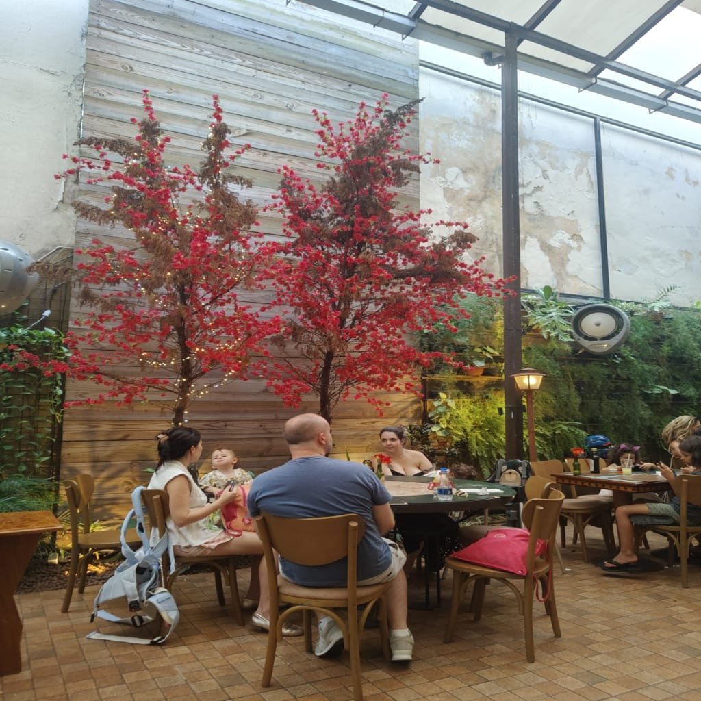 Área interna do Jardim Secreto com mesas, cadeiras e ambiente decorado com plantas