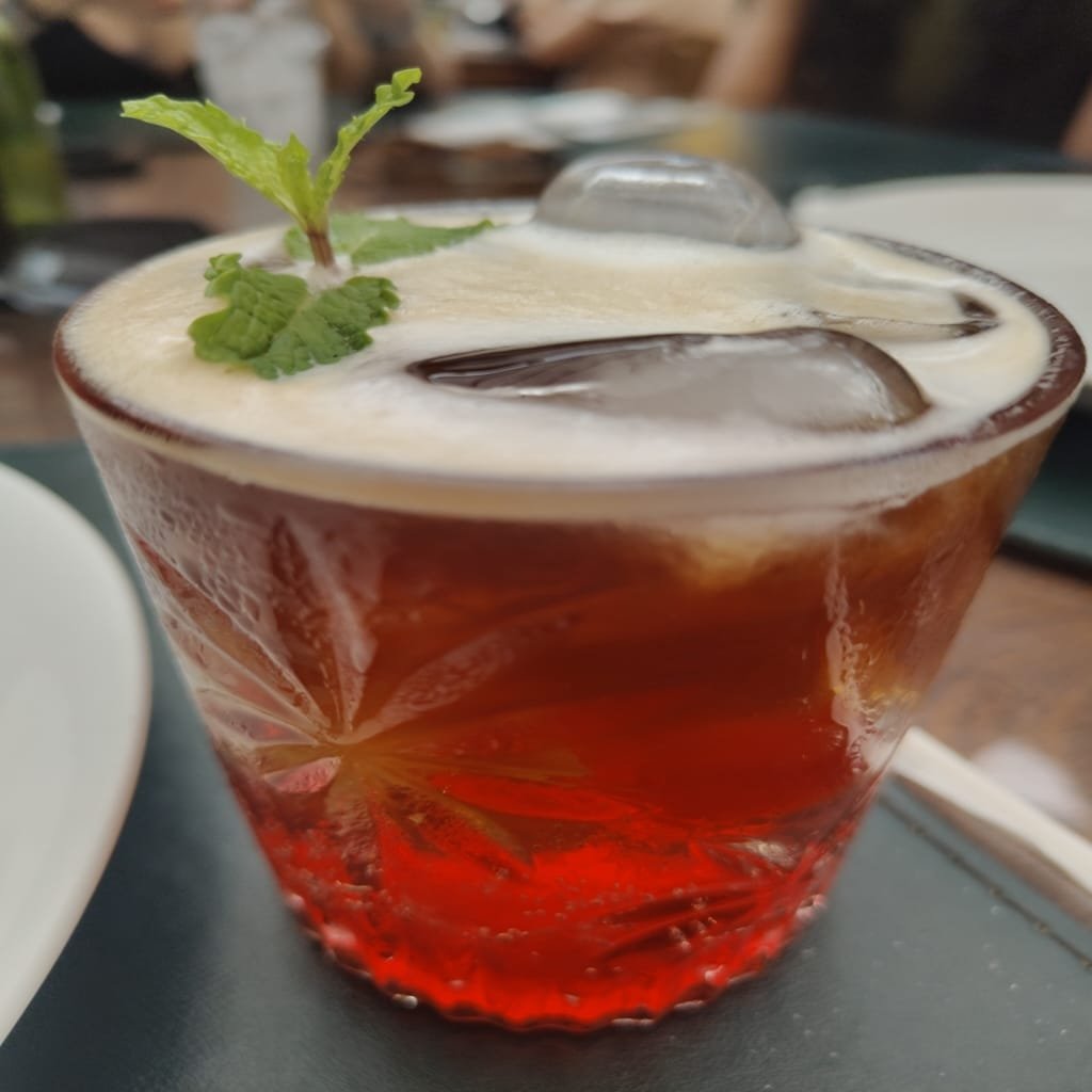 Drink colorido servido no Jardim Secreto com gelo e folha de hortelã decorativa