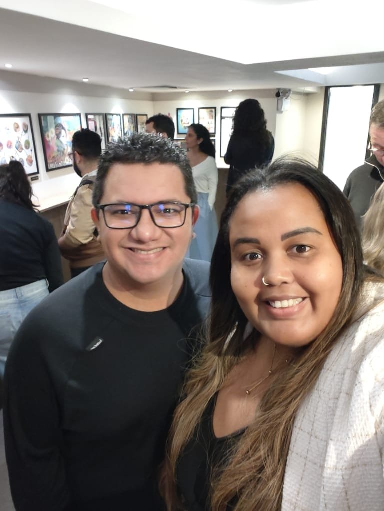 Um passeio imperdível no Teatro Clara Nunes na Gávea: espetáculo 8 Casal sorridente no foyer do Teatro Clara Nunes, com exposição de cartazes ao fundo e público circulando