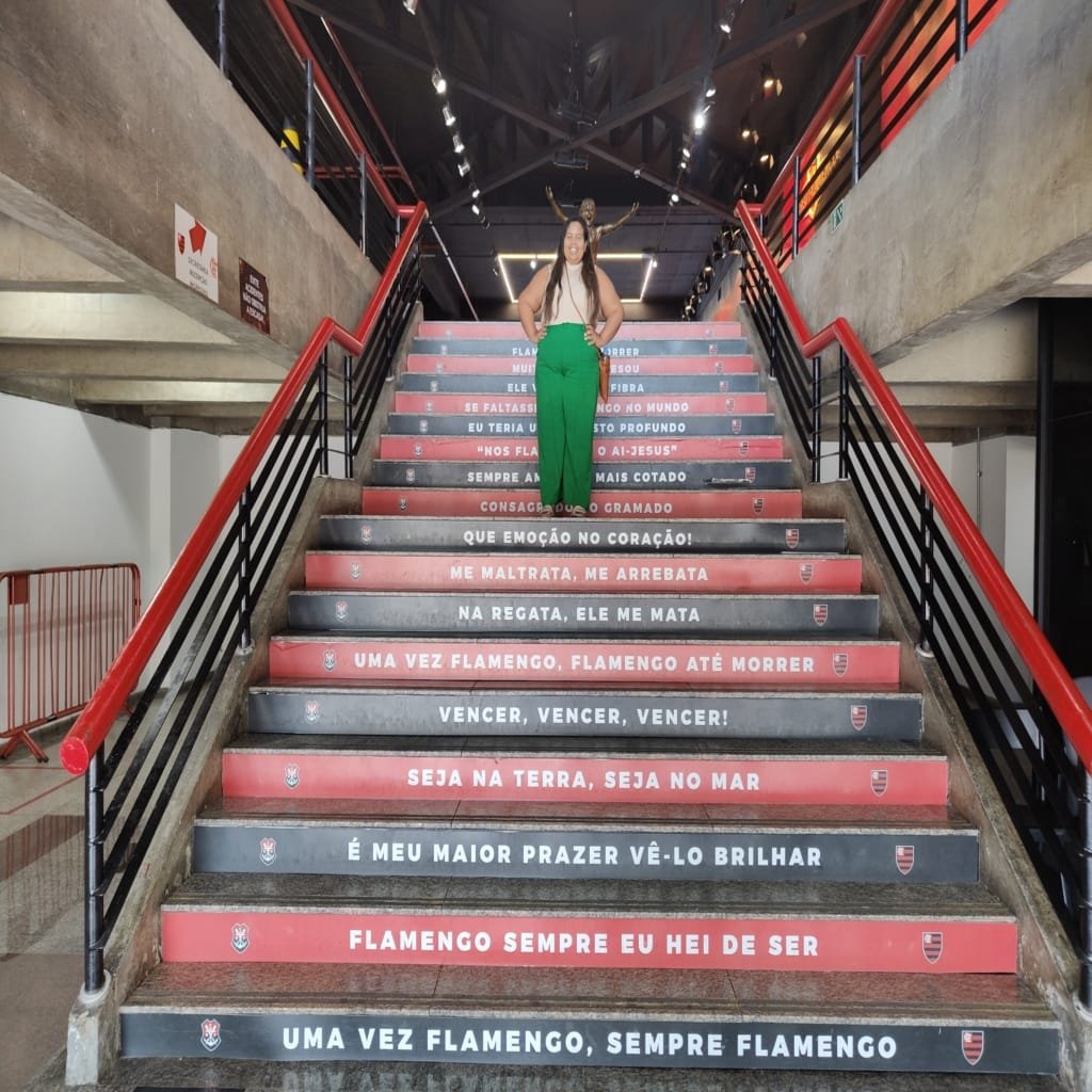 Escadaria interna do Museu do Flamengo com frases marcantes do hino do clube nas cores vermelho e preto.