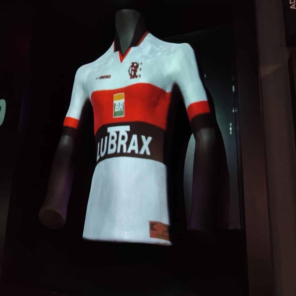 Camisa histórica do Flamengo com patrocínio Lubrax, exposta em vitrine iluminada dentro do museu.