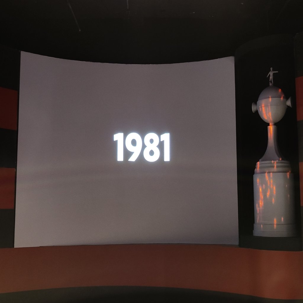 Tela projetando o ano 1981 ao lado de réplica da taça da Libertadores no Museu do Flamengo.