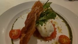 Entrada refinada servida no Restaurante Terraço Itália em São Paulo com burrata, rúcula, tomate cereja e massa crocante decorada com azeite e pesto
