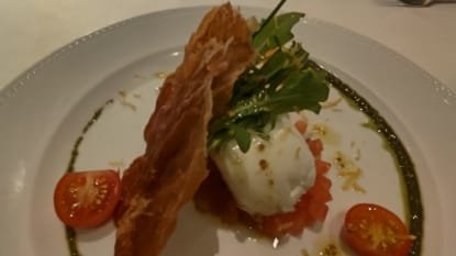 Entrada refinada servida no Restaurante Terraço Itália em São Paulo com burrata, rúcula, tomate cereja e massa crocante decorada com azeite e pesto