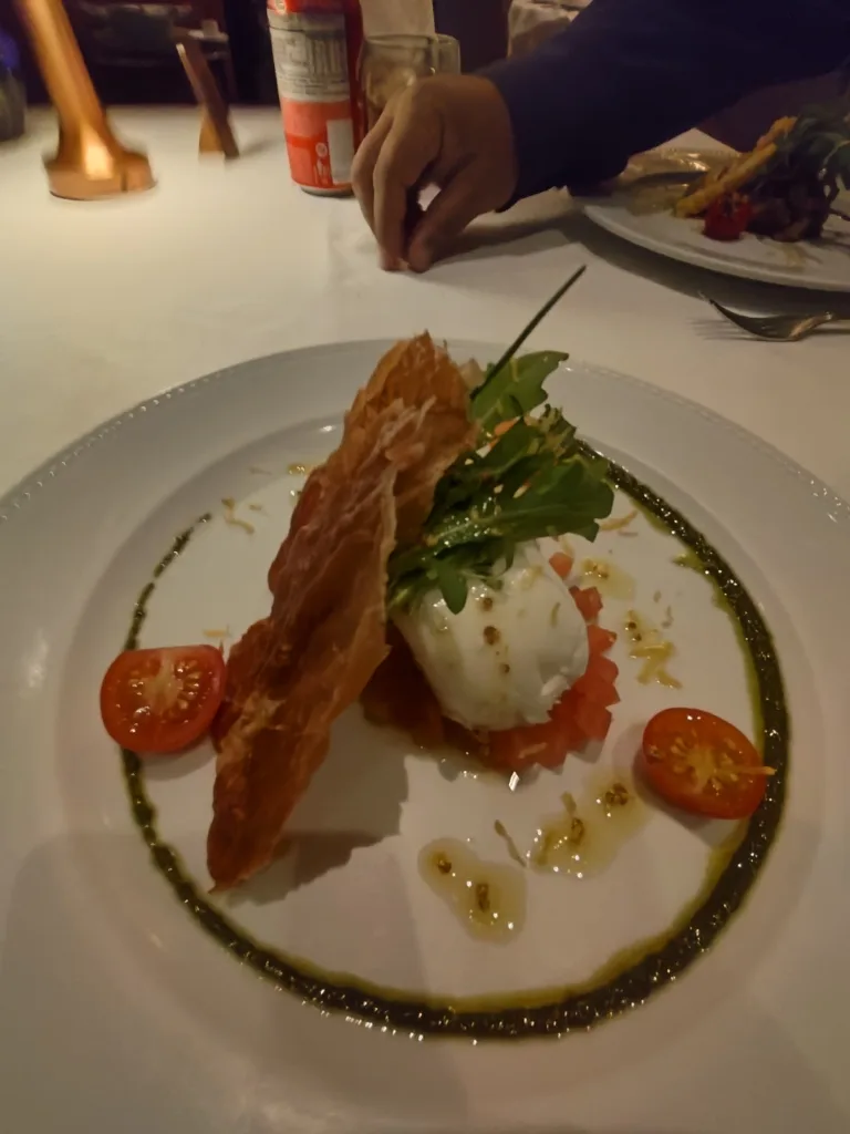 Terraço Itália SP: vale a pena? Preços, cardápio, vista e experiência 7 Entrada refinada servida no Restaurante Terraço Itália em São Paulo com burrata, rúcula, tomate cereja e massa crocante decorada com azeite e pesto