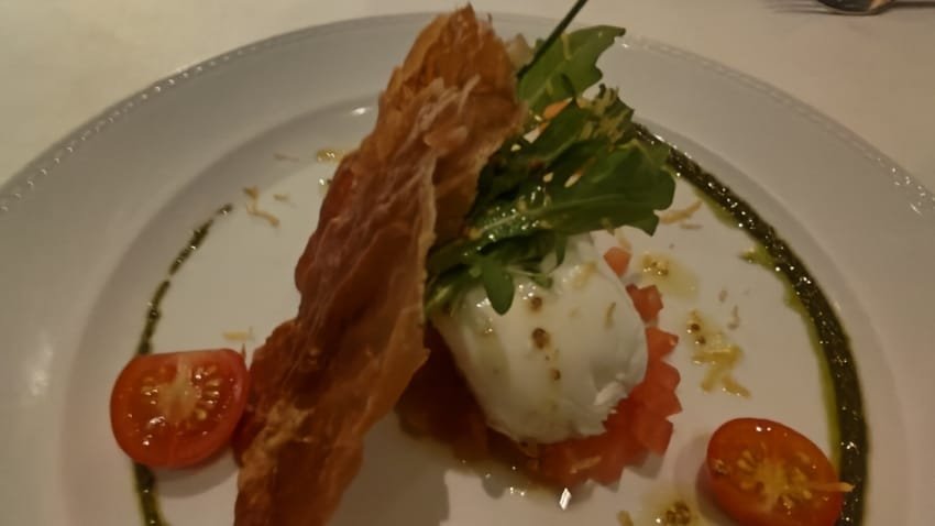 Entrada refinada servida no Restaurante Terraço Itália em São Paulo com burrata, rúcula, tomate cereja e massa crocante decorada com azeite e pesto