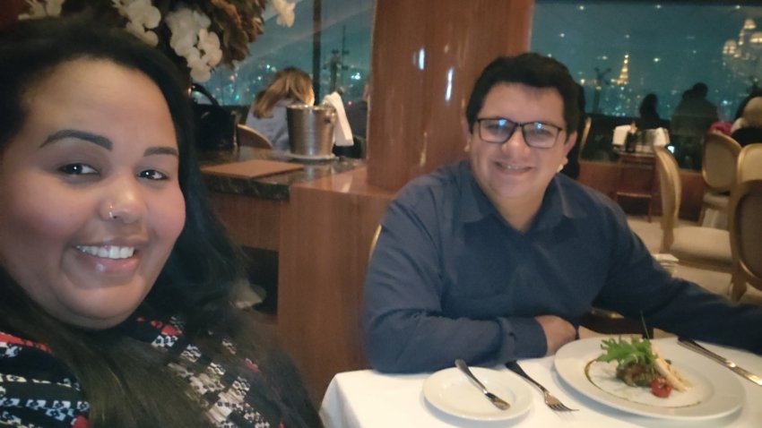 Terraço Itália Restaurant in São Paulo: Our Full Experience + Prices + Menu + 7 Reasons to Visit 1 Couple dining at Terraco Italia with gourmet dishes on the table and a panoramic nighttime view of São Paulo in the background.