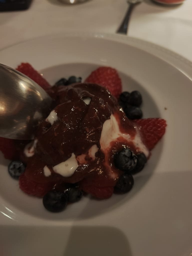 Sobremesa de frutas vermelhas com calda de chocolate e creme branco servida no Terraço Itália em prato branco elegante