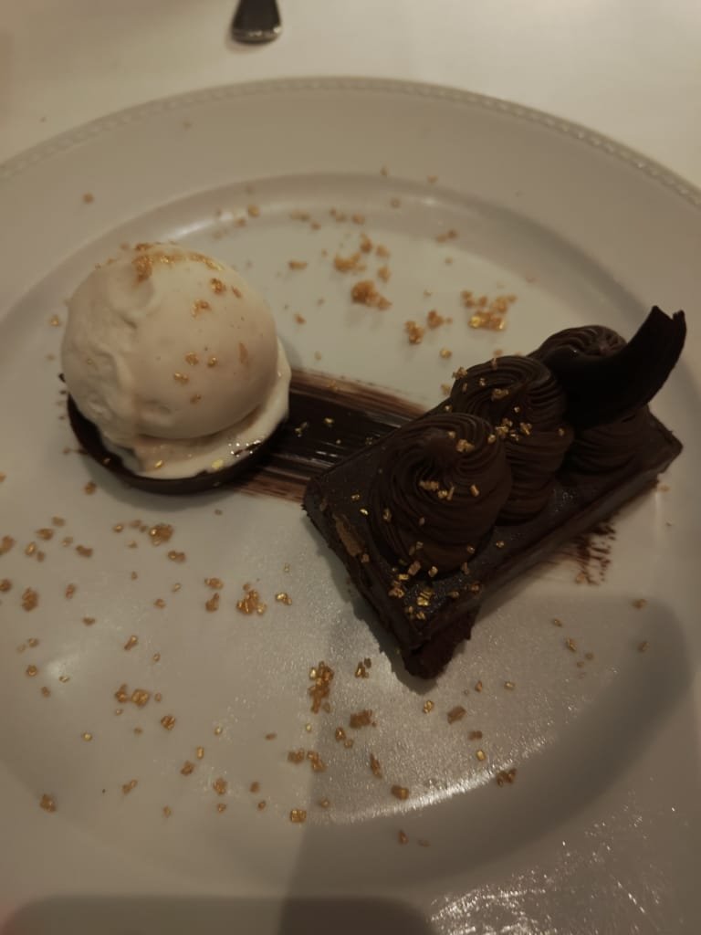 Sobremesa gourmet de chocolate com sorvete e detalhes dourados servida com apresentação sofisticada