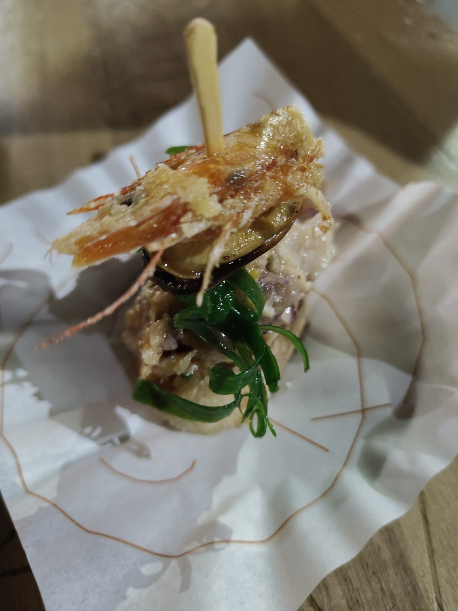 Pintxo elaborado com camarão, mexilhão e ervas frescas, finalizado com um toque crocante