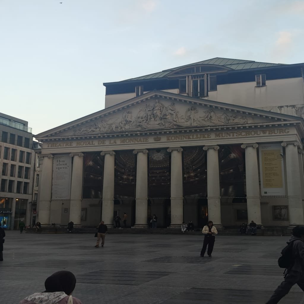 Fachada clássica do Théâtre Royal de la Monnaie em Bruxelas, com colunas e esculturas históricas na praça central mostrando o que fazer em bruxelas