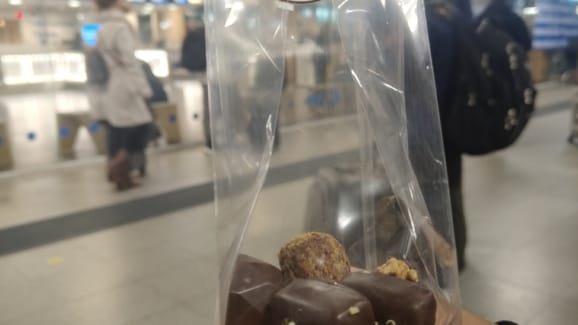 Embalagem de chocolates belgas Corné Port-Royal sendo segurada em um terminal de aeroporto em Bruxelas.