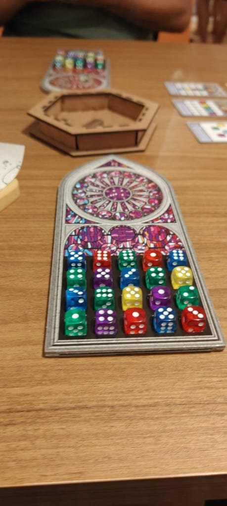 Jogo de tabuleiro com dados coloridos sendo jogado em uma mesa da Luderia Carioca, retratando a experiência divertida do espaço no Rio de Janeiro.