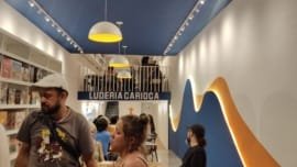 Interior da Luderia Carioca no Rio de Janeiro, com prateleiras cheias de jogos de tabuleiro e visitantes aproveitando o ambiente moderno e acolhedor.