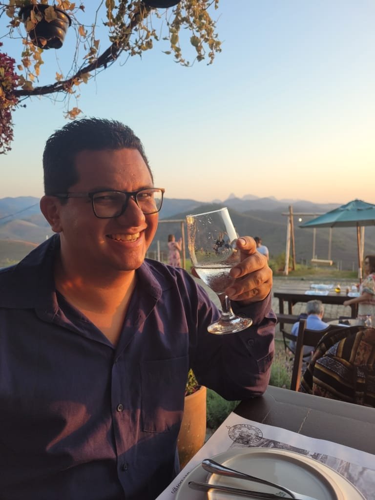 Momento de celebração na Borgo del Vino em Areal com taça de vinho e vista para as montanhas ao entardecer