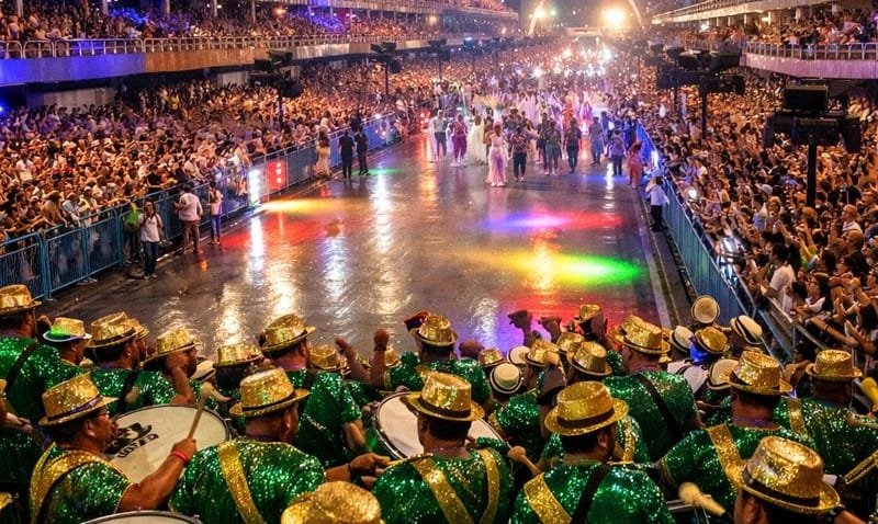 Ensaios técnicos do Carnaval 2026 na Sapucaí com escolas de samba desfilando sob luzes coloridas e público vibrando no Rio de Janeiro.