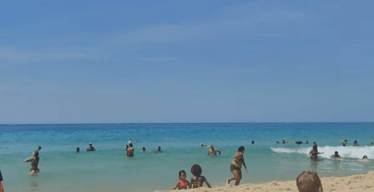 Praia de Ipanema no Rio de Janeiro em um dia ensolarado com pessoas aproveitando o mar