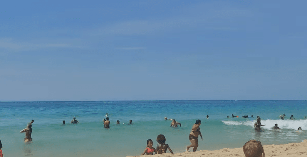 Praia de Ipanema no Rio de Janeiro em um dia ensolarado com pessoas aproveitando o mar