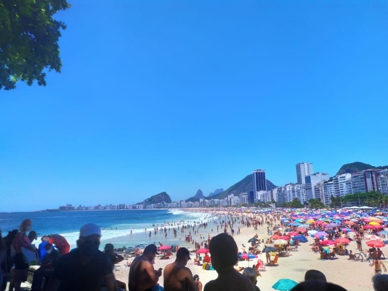 Praias do Rio para Surfe: Guia Completo com Dicas Locais (2026) 3 Praias do Rio de Janeiro no verão com Copacabana e Ipanema cheias em dia de sol