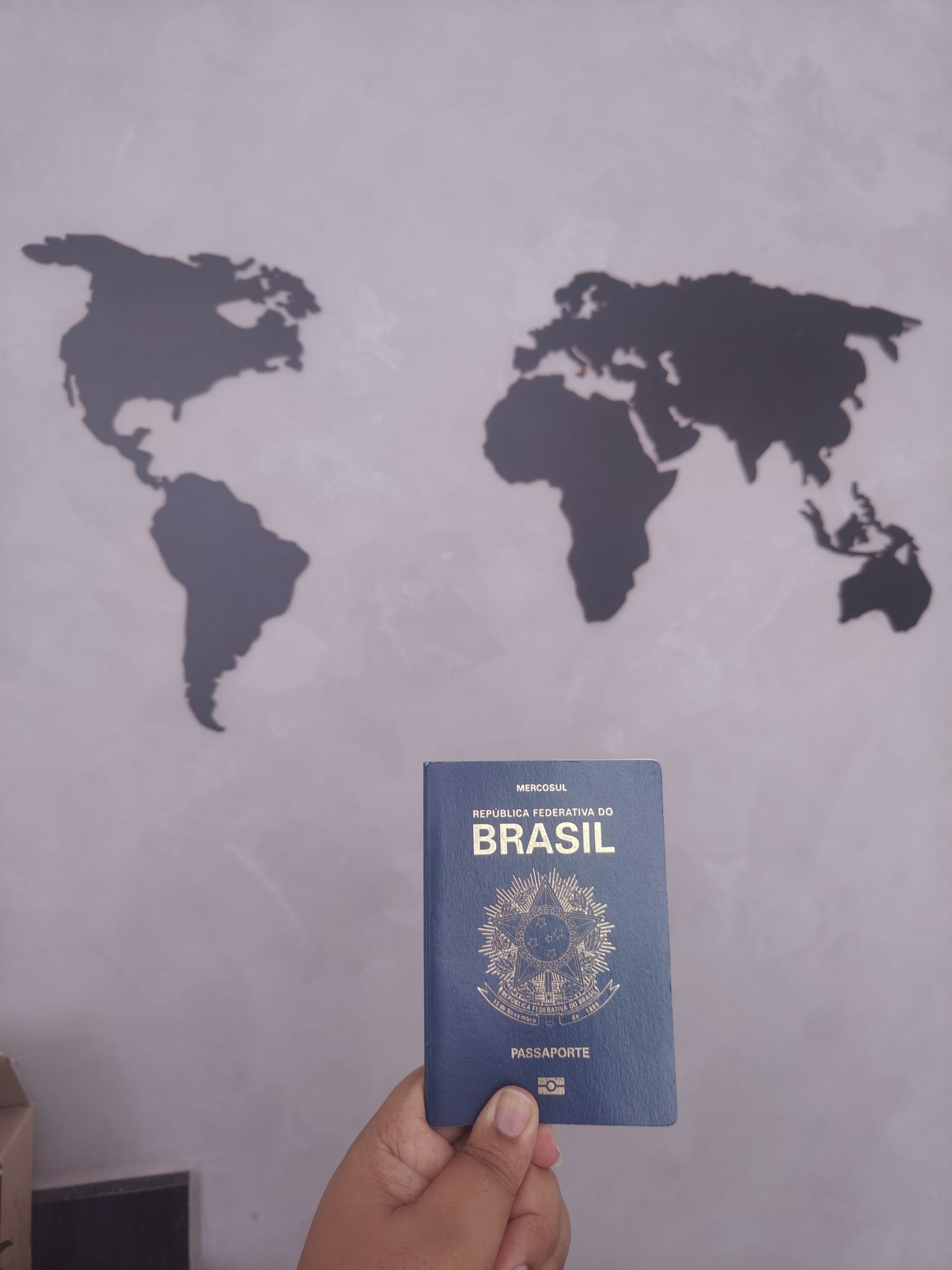 passaporte brasileiro em frente a mapa do mundo representando destinos de viagem internacionais
