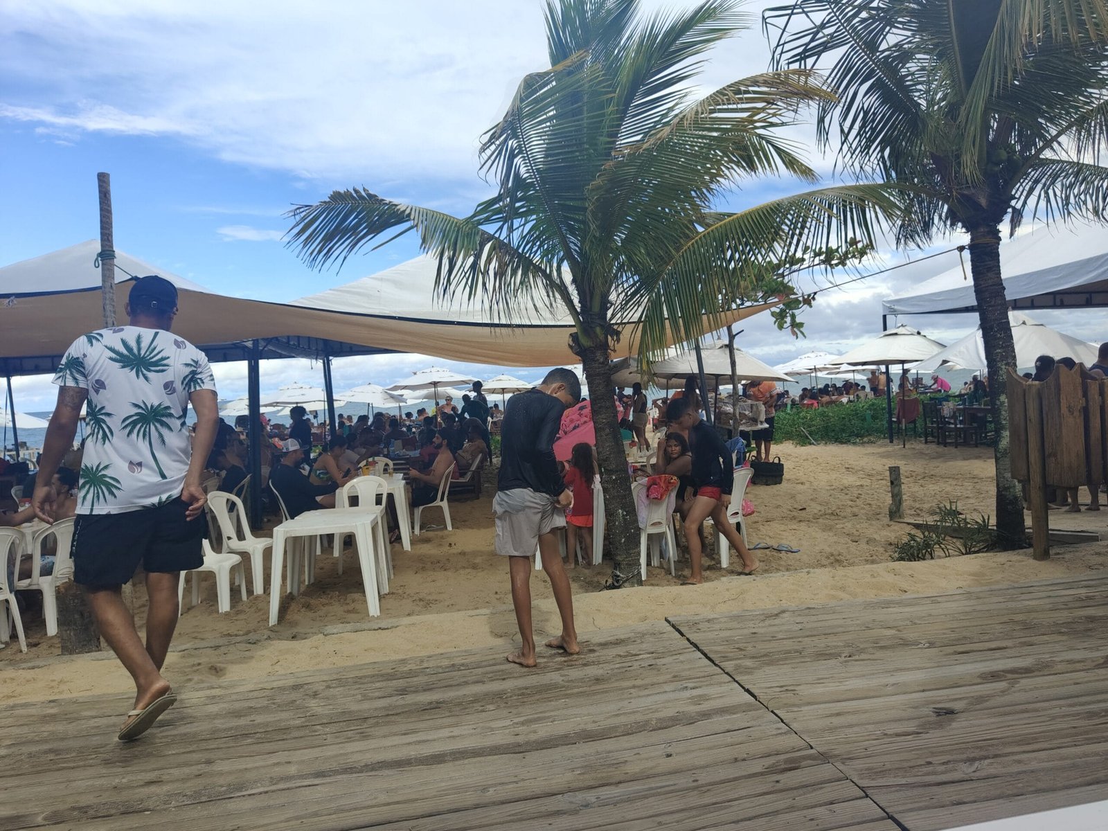 Praia de Taperapuã em Porto Seguro com barracas estruturadas, mesas na areia e movimento de turistas.